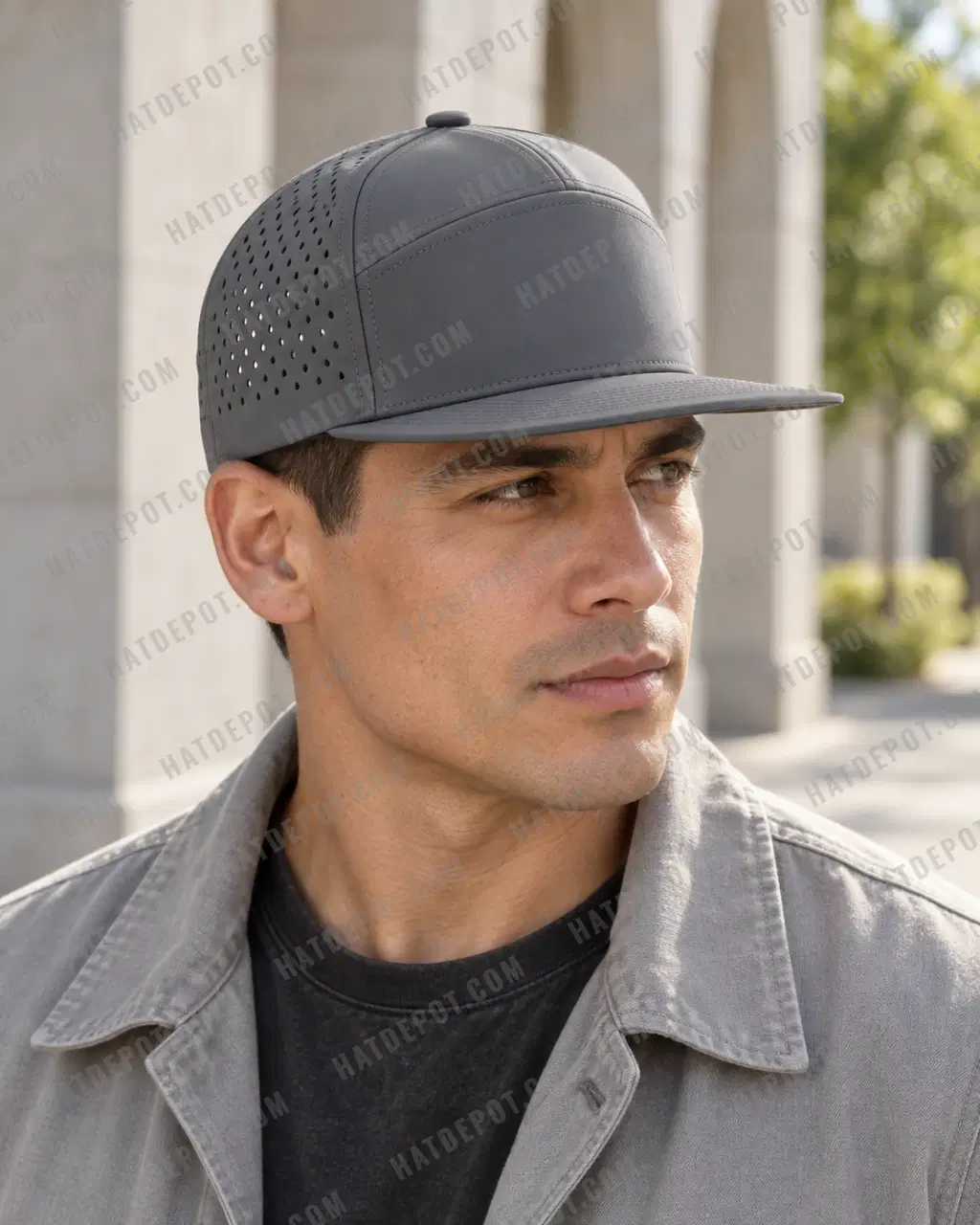 Close daylight three-quarter profile of a model wearing the charcoal Seven-Panel Perforated Snapback, showing the flat brim, seamless front and divided solid crown panels.